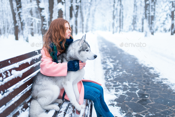 Happy woman sitting on the bench with husky - Stock Photo - Images