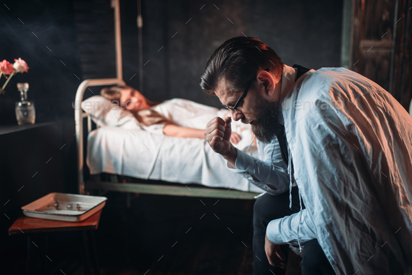 Tired man against sick woman in hospital bed - Stock Photo - Images