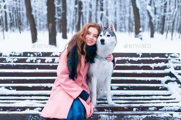 Happy woman sitting on the bench with husky - Stock Photo - Images