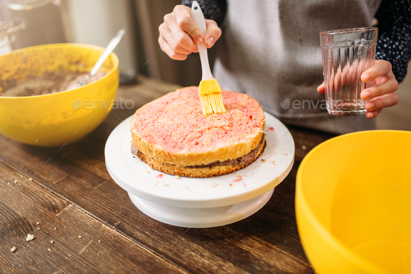 Woman cook hands smears filling for cake - Stock Photo - Images