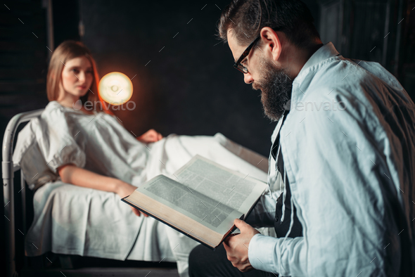 Man reading book against ill woman in hospital bed - Stock Photo - Images