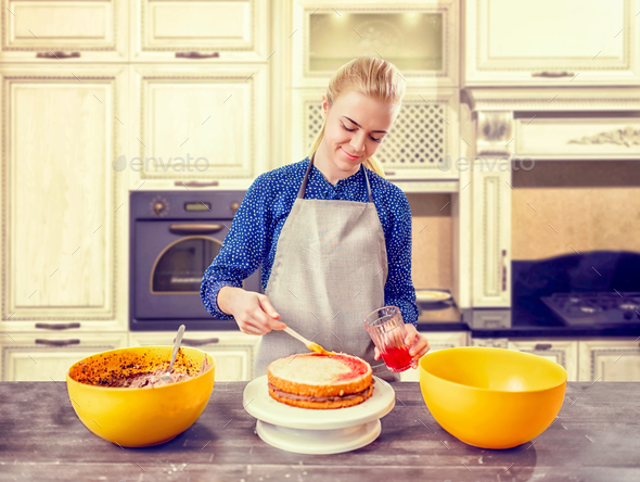 Woman cook smears baked cake with berry syrup - Stock Photo - Images