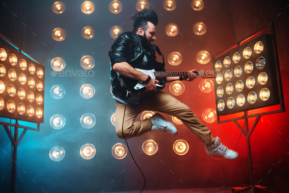 Male performer with electro guitar in a jump