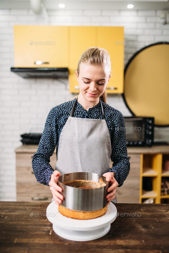 Woman cook in apron takes the form of a baked cake - Stock Photo - Images