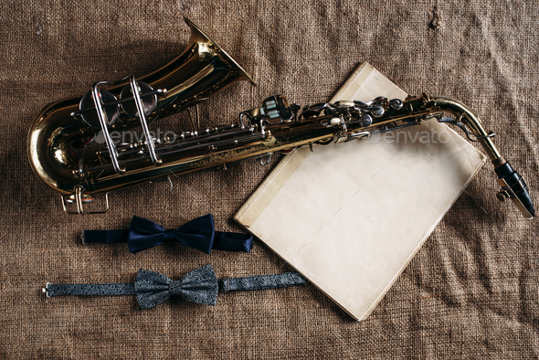 Saxophone, notes and bowtie on canvas background - Stock Photo - Images