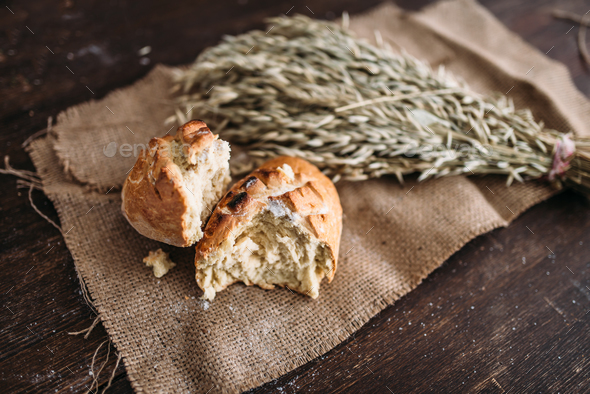 Bread loaf breaked in half, wheat on burlap cloth - Stock Photo - Images