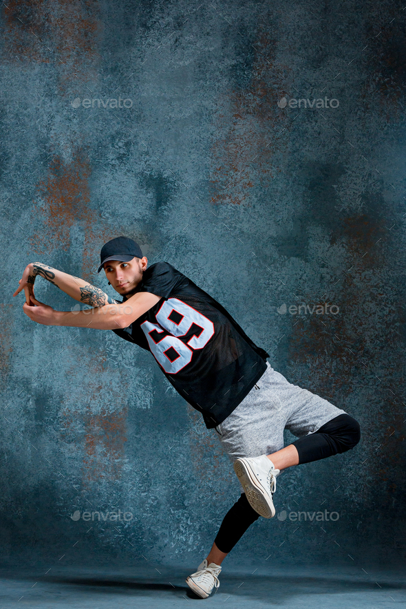 Young man break dancing on wall background. Stock Photo by master1305