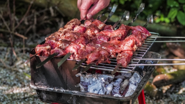 Raw Meat Marinated in Tomato and Onion on the Skewers on the Grill. Turning Servings of Barbecue alt