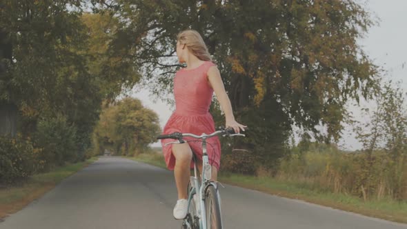 Beautiful Girl Riding a Bicycle on a Road.