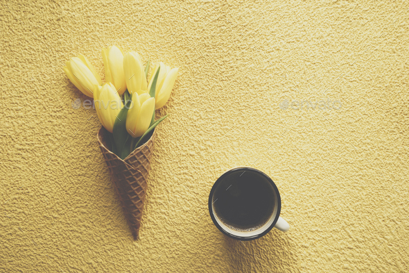Tulips in ice cream cone on yellow background