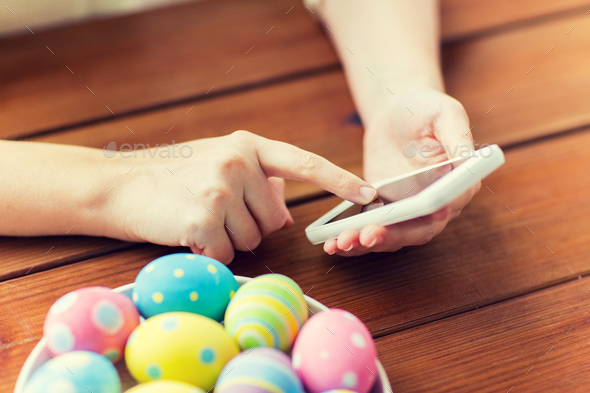 close up of hands with easter eggs and smartphone - Stock Photo - Images