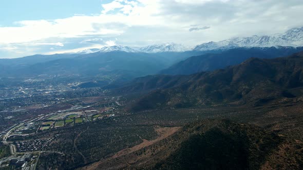 Aerial orbit of the foothills at Morro Las Papas, Las Condes, Santiago, Chile. Snowy Andes mountain alt