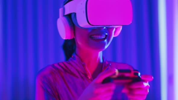 Young asian woman is using virtual reality headset. Neon light studio portrait alt