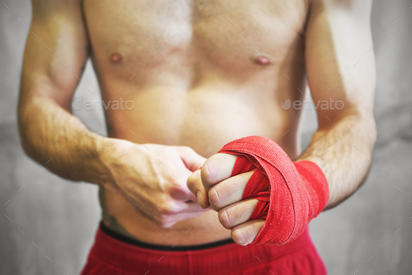 Man is wrapping hands with red boxing wraps. Stock Photo by sianstock