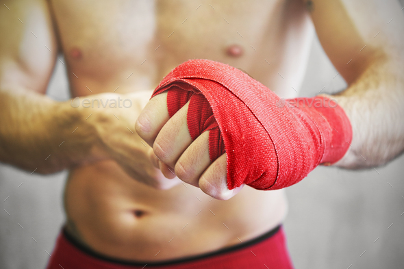 Man is wrapping hands with red boxing wraps. Stock Photo by sianstock