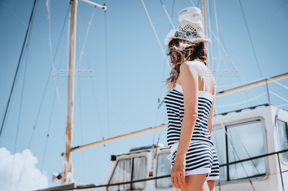 Woman in striped clothes standing near yacht in sunny summer day. - Stock Photo - Images