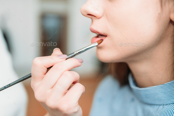 Make up artist hand applying gloss on woman lips - Stock Photo - Images