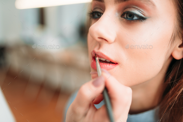Make up artist hand applying gloss on woman lips - Stock Photo - Images