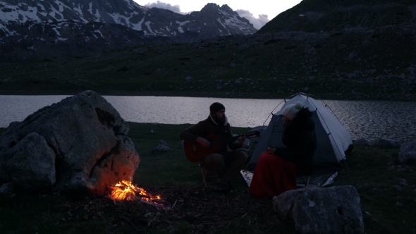 Couple of Travelers at Dusk Near a Campfire alt