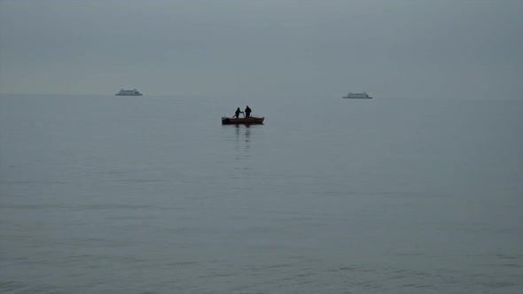 Fishermen On A Boat On The Background Of Ferries That Float Past  alt