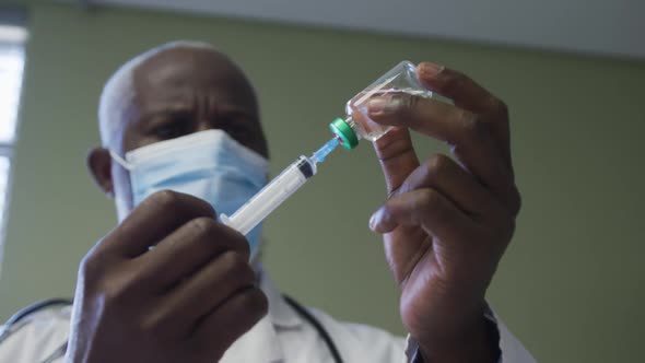 African american male doctor wearing face mask preparing injection alt