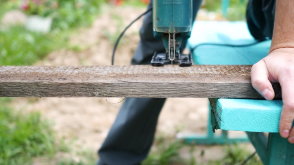 Man Saws a Board Using a Jig Saw