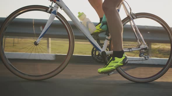 Side View of the Wheel of a Bicyclist Riding on the Highway Against the Background of the Sunset alt