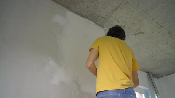A Young Man in a Yellow Tshirt is Doing a Walls Renovation in His Home alt