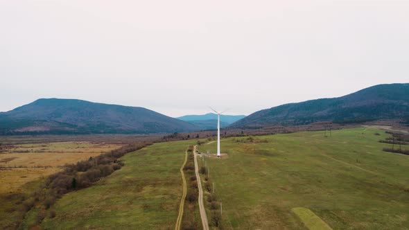 Large windmill rotates in the mountains of the Carpathians against a backdrop of cloudy sky