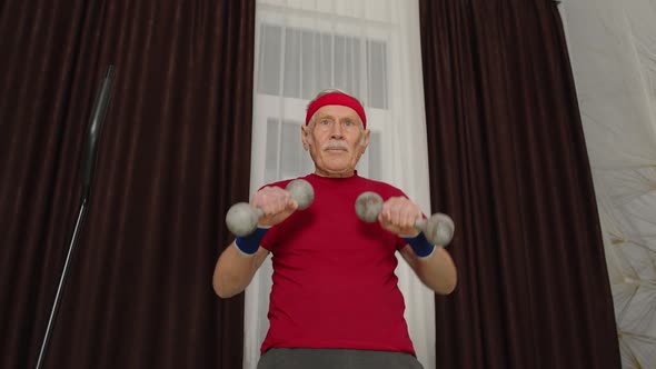 Senior Elderly Man in Sportswear Doing Weight Lifting Dumbbells Workout Cardio Exercising at Home alt
