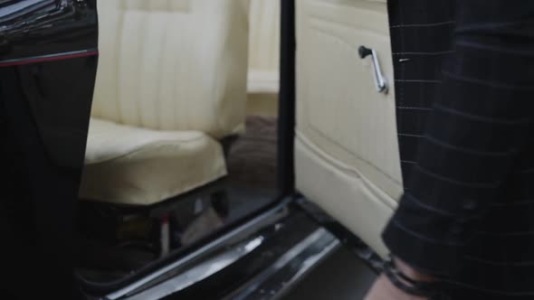 Charismatic Macho Opens Door and Sits Into Luxury Retro Car alt