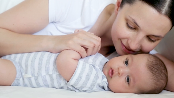 Mom Lies in Bed with a Newborn Who Yawns alt