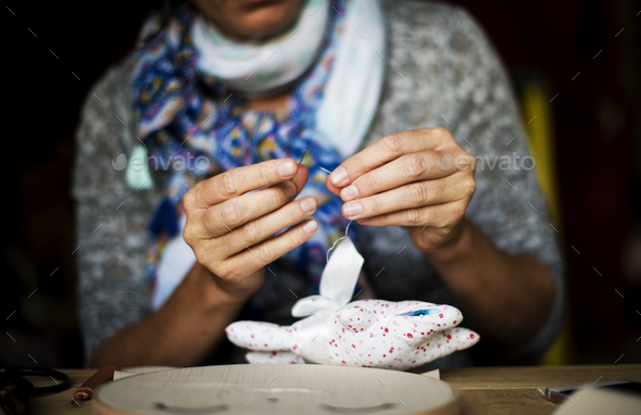 Woman sewing handmade doll on the table