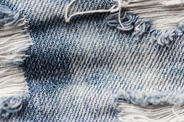 close up of holes on shabby denim or jeans clothes