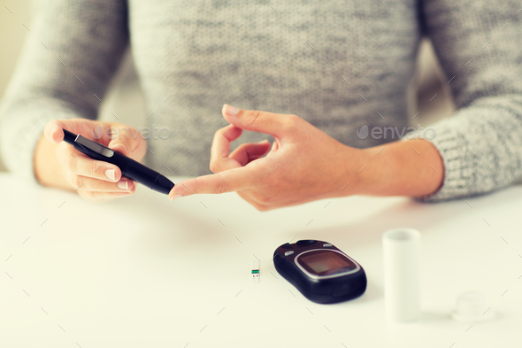 close up of woman making blood test by glucometer - Stock Photo - Images
