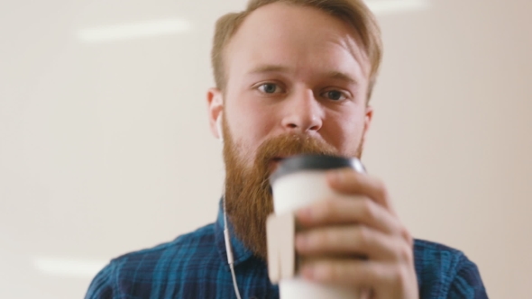 Hipster Drinking Coffee at Desk in Creative Office