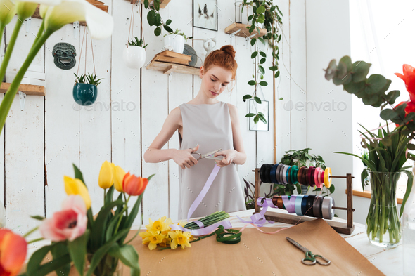 Woman using scissors to cut ribbon for bouquet
