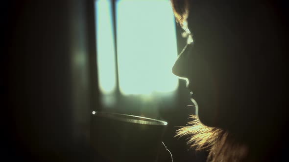 Silhouette of Woman Enjoying Coffee at Sunset at Home Steam From a Glass Sun Rays Close Up Cinematic