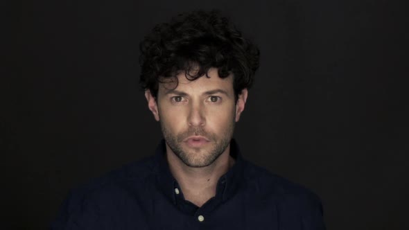 Man shushing with fingers held to lips alt