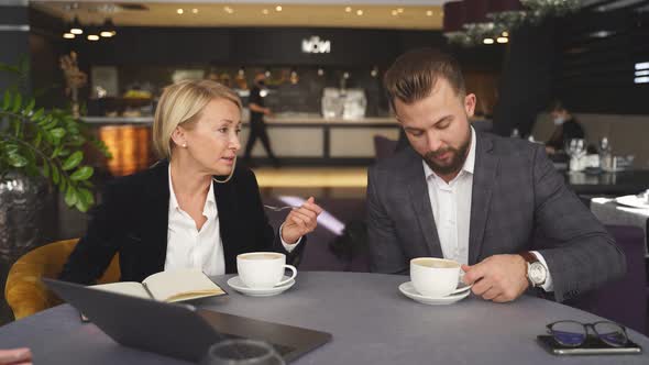 Conversation Between Business People Dressed in Suits Sitting with Coffee in Hotel Restaurant