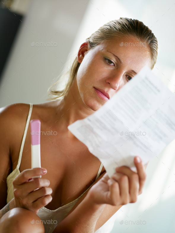 Young Woman Looking At Pregnancy Test Instructions