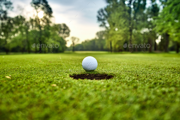Golf ball on the green. golf ball on lip of cup - Stock Photo - Images