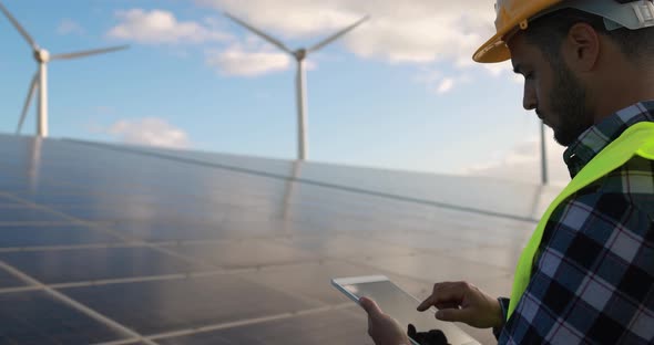 Young man working with digital tablet inside wind farm - Ecology concept alt