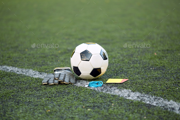 ball, gloves, whistle and cards on soccer field
