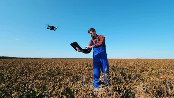 Withered Field and an Agriscientist Operating a Drone alt
