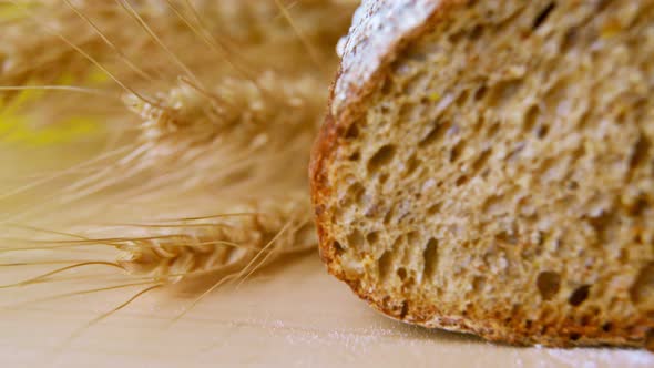 Dark Bread Cut Into Slices on a Wooden Board with Breadcrumbs Closeup alt
