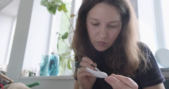 Woman Making Doll Ceramic Part. Female Sitting and Creating Ear for Doll at Home at Table. Pottery alt