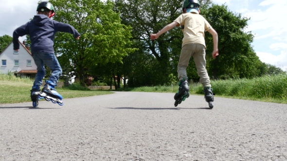 Two Boys in Helmets Learning To Drive Roller Skates in Summer, Stock ...