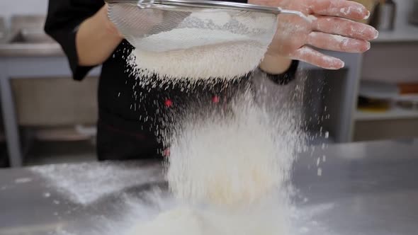 Closeup of a Female Cook Sifting Flour Through a Sieve in the Kitchen alt