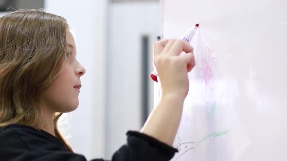 A Little Teenage Girl Goes to School Draws with a Marker on the Blackboard alt